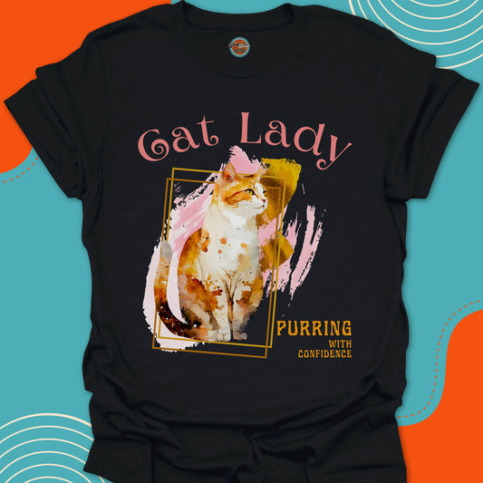 black t-shirt with a orange and white cat graphic on a colorful artsy background design and "Cat Lady, purring with confidence" text