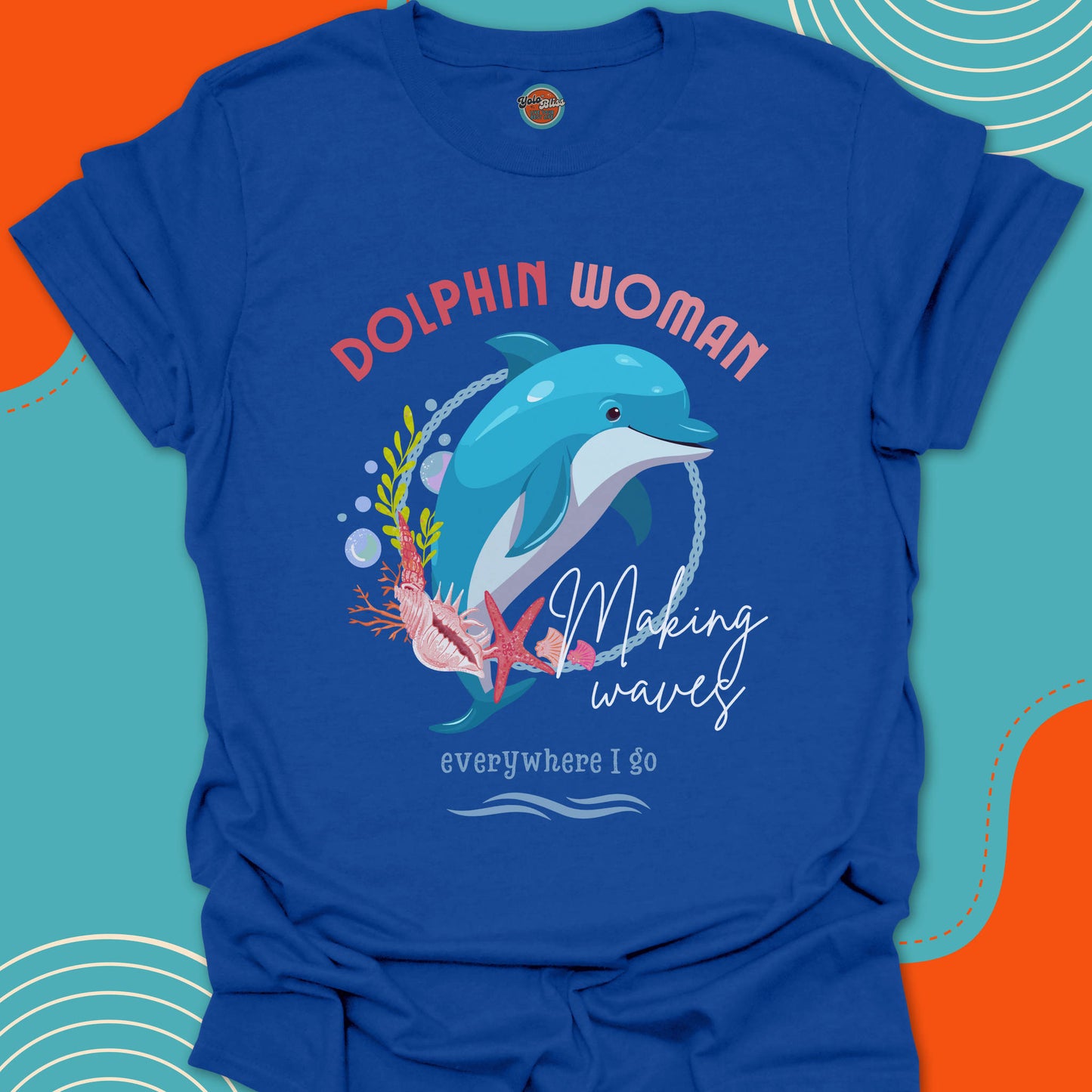 Royal blue t-shirt with a jumping dolphin graphic and "Dolphin woman, making waves everywhere i go" text on an oceanic background