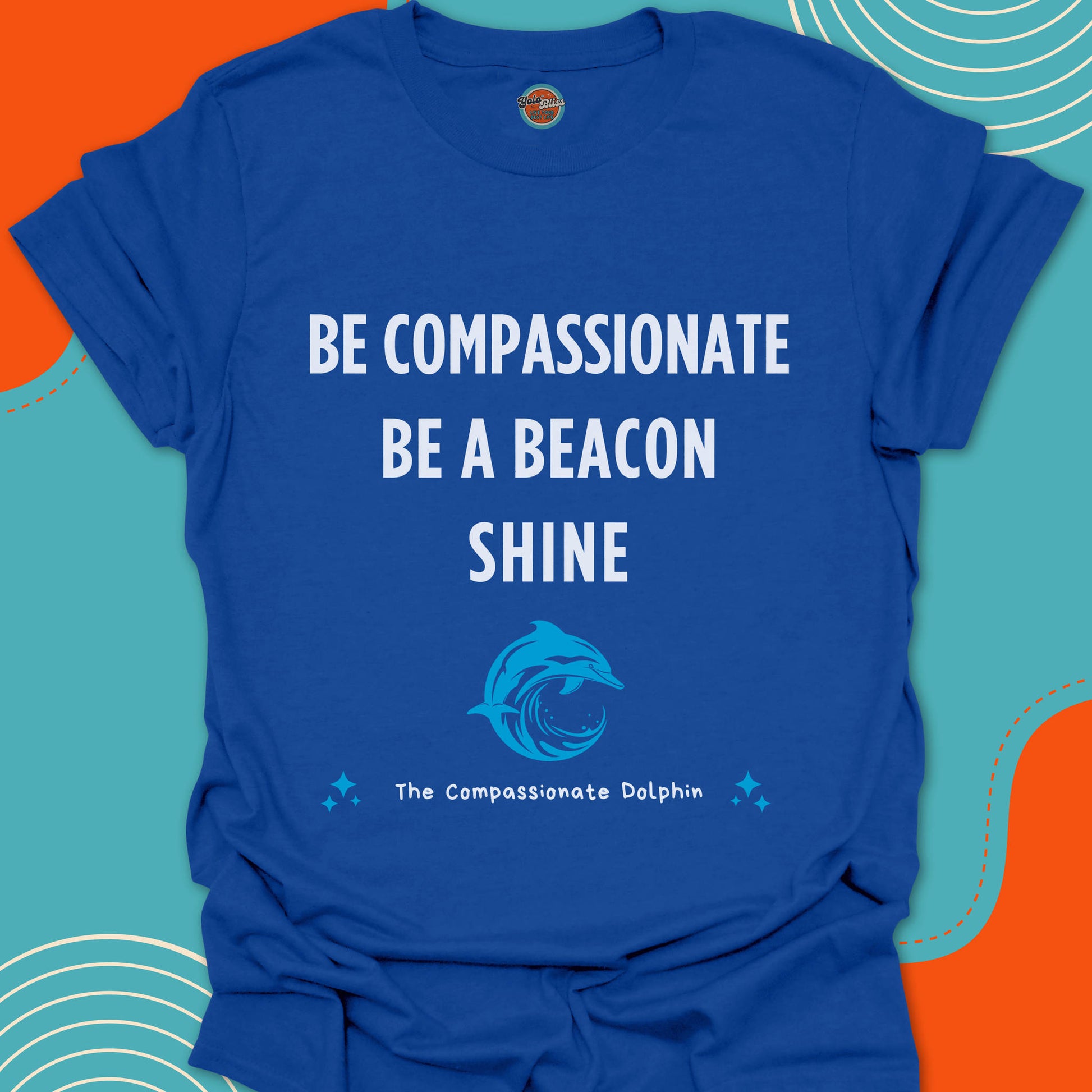 Royal blue t-shirt with motivational text "Be compassionate, be a beacon, shine"and shiny blue dolphin in the ocean graphic