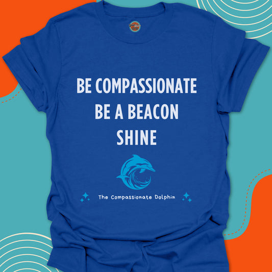Royal blue t-shirt with motivational text "Be compassionate, be a beacon, shine"and shiny blue dolphin in the ocean graphic
