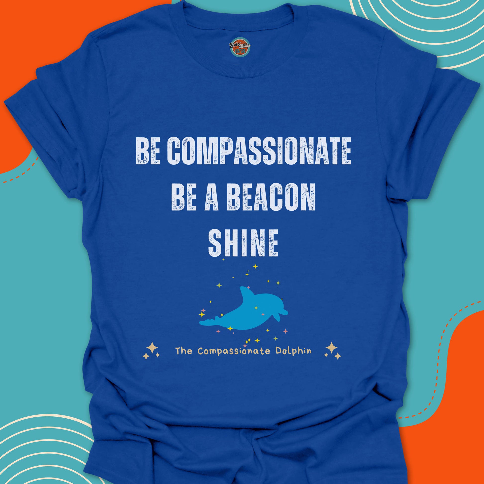 Royal blue t-shirt with motivational text "Be compassionate, be a beacon, shine"and blue dolphin swimming in the ocean graphic