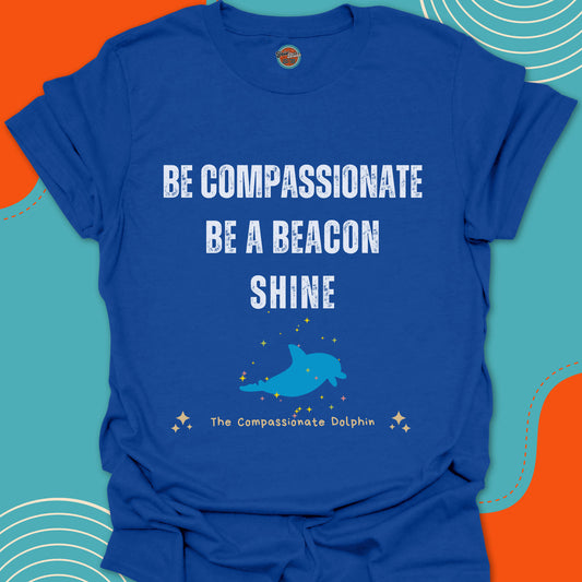 Royal blue t-shirt with motivational text "Be compassionate, be a beacon, shine"and blue dolphin swimming in the ocean graphic
