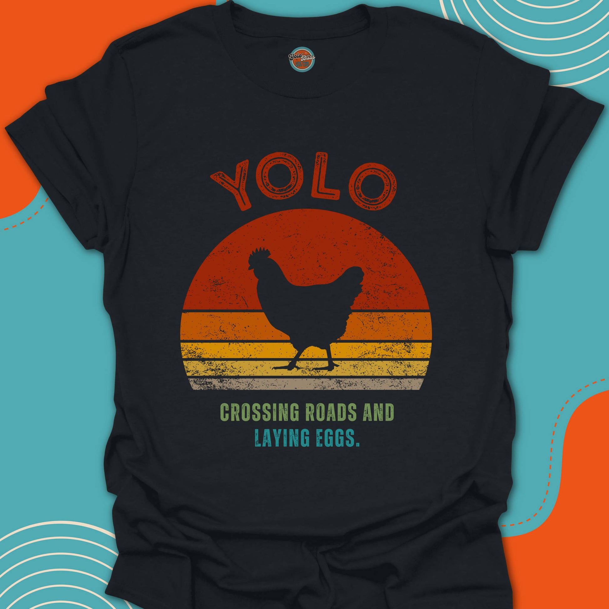 Black t-shirt with a chicken crossing the road graphic and 'YOLO' crossing roads and laying eggs text on a red orange and yellow circular background