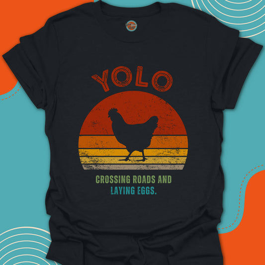 Black t-shirt with a chicken crossing the road graphic and 'YOLO' crossing roads and laying eggs text on a red orange and yellow circular background