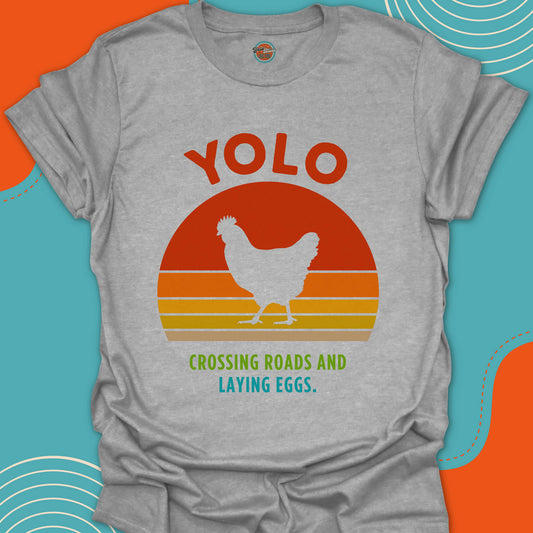 Gray t-shirt with a walking chicken graphic and "crossing roads and laying eggs" text on a popular warm sunset background