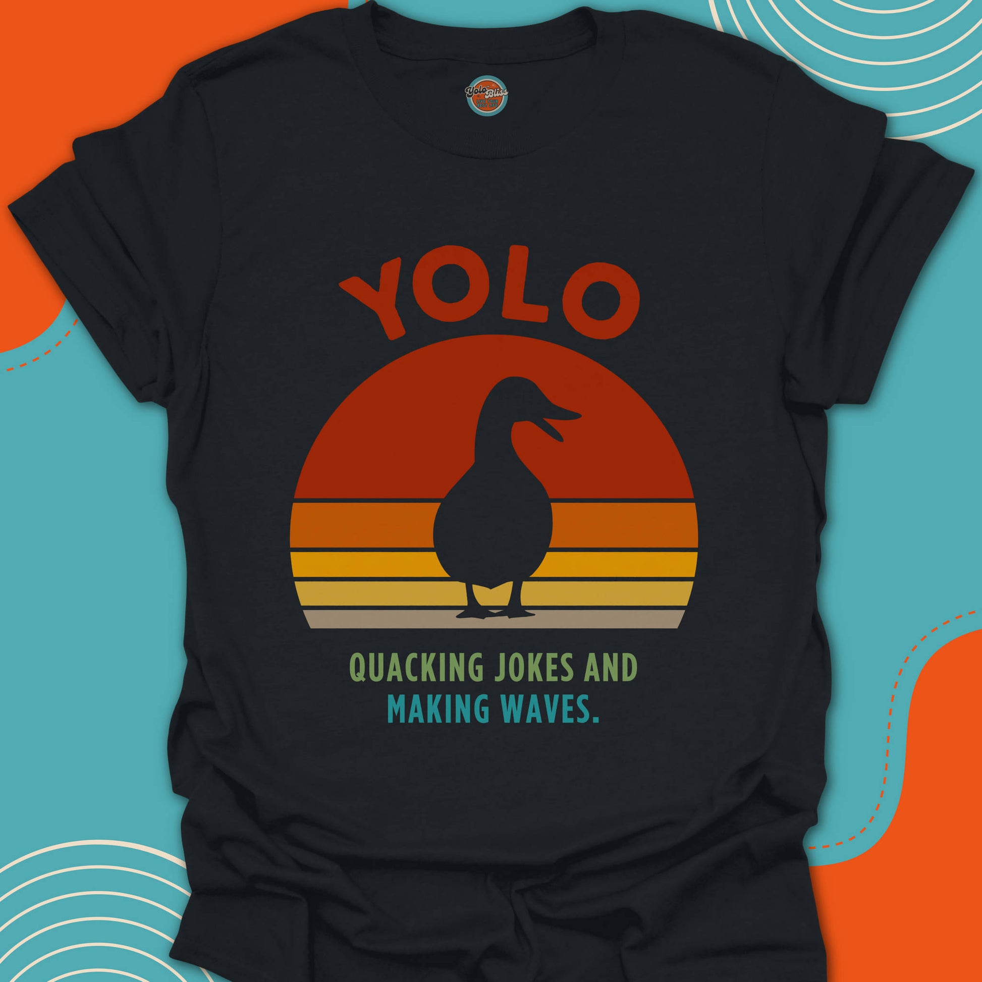 Black t-shirt with a duck silouhette graphic and "quacking jokes and making waves" text on a beautiful sunset background