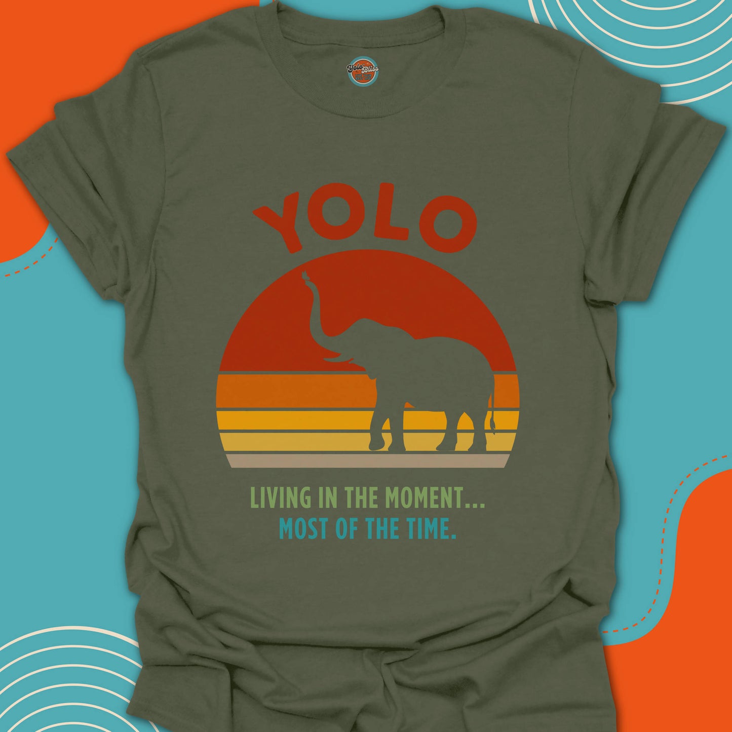 Green t-shirt with a elephant graphic and "YOLO living in the moment, most of the time" text on a red, orange and yellow sunset background