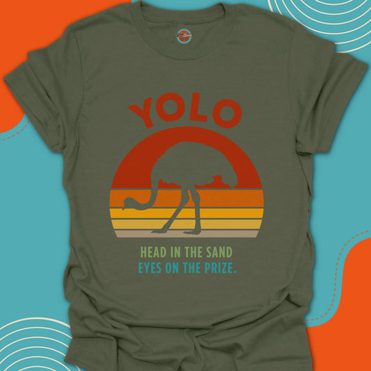 Military Green t-shirt with 'YOLO head in the sand eyes on the prize' text and ostrich silhouette graphic design on a colorful warm sunset background
