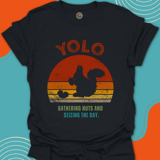 Black t-shirt with a graphic of a squirrel eating acorn and text 'YOLO gathering nuts and seizing the day' on a trendy warm sunset background.